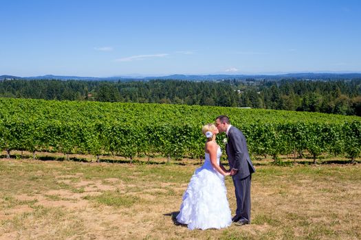 A bride and groom share a kiss after their ceremony on their wedding day at a vineyard winery in Oregon outdoors.