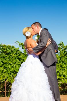 A bride and groom seal the deal with a kiss during their wedding day ceremony at a vineyard winery in Oregon.