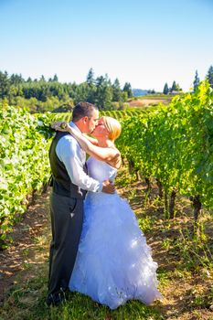 A bride and groom share a kiss after their ceremony on their wedding day at a vineyard winery in Oregon outdoors.