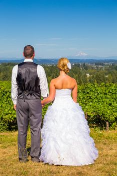 A bride and groom enjoy a view of mount hood in the background from this high elevation winery vineyard in Oregon just outside of Portland.