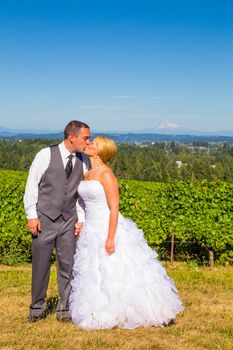 A bride and groom enjoy a view of mount hood in the background from this high elevation winery vineyard in Oregon just outside of Portland.