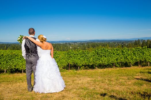 A bride and groom enjoy a view of mount hood in the background from this high elevation winery vineyard in Oregon just outside of Portland.