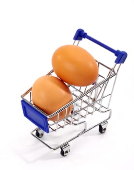 Fresh eggs in shopping cart over white 