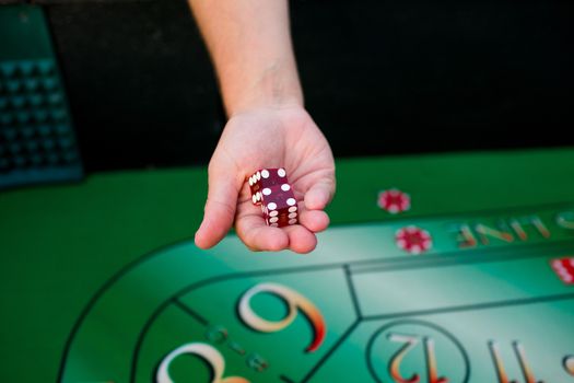 A groom holds dice above a craps table at his casino themed wedding reception.