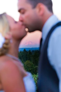 A bride and groom kiss during sunset with Mount Hood in the background at their wedding.