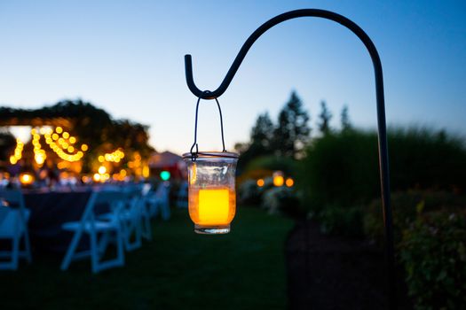 A candle lights up some space at a wedding reception at dusk.