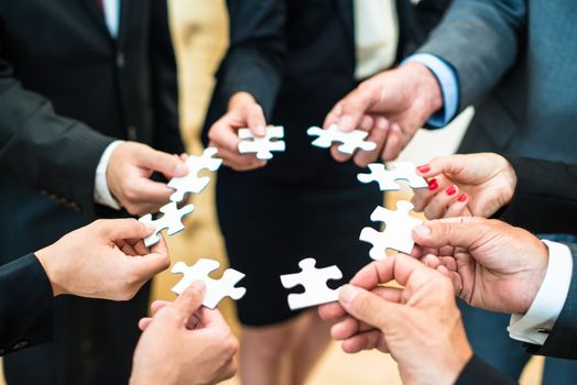 Teamwork - a group of eight business people assembling a jigsaw puzzle - representing team support and help concepts