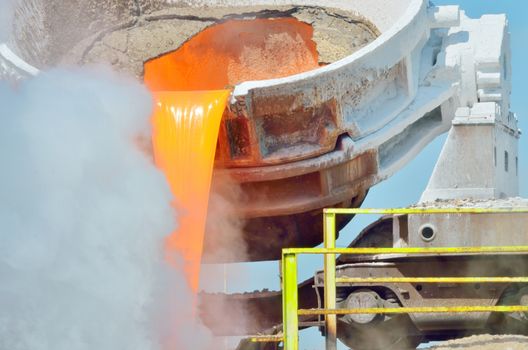 The molten slag is poured from a cup on a railway platform