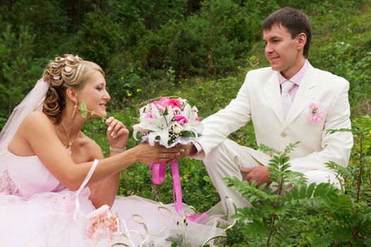 The groom in white suit and the bride in a pink dress on nature