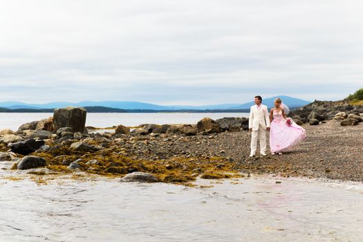 The groom in white suit and the bride in a pink dress on nature