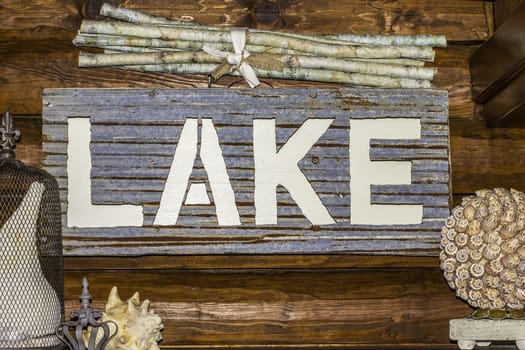 A sign showing the word "LAKE" hanging from a log cabin.