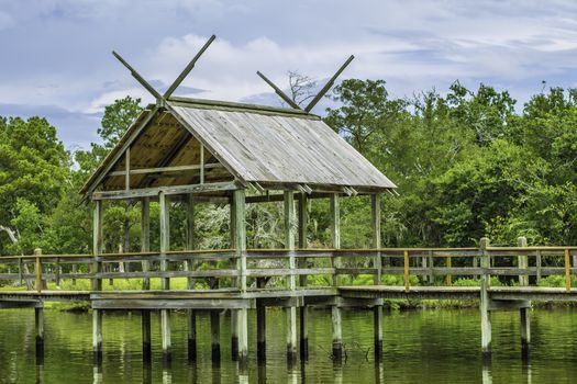 Small fishing pier among a calm lake with trees draped behind it.