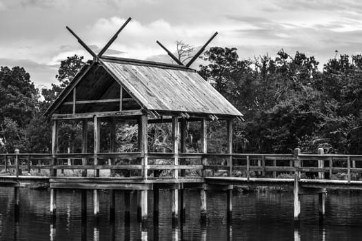 Small fishing pier among a calm lake with trees draped behind it.