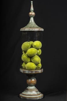A decorative vintage glass jar filled with limes.