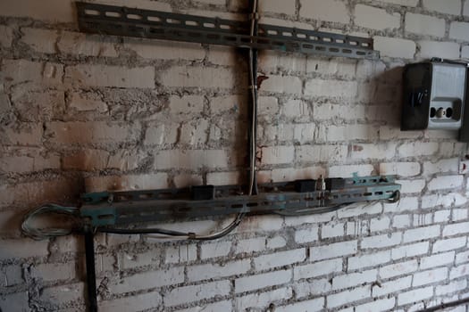 Electrical wiring in a dangerous condition on the brick wall background