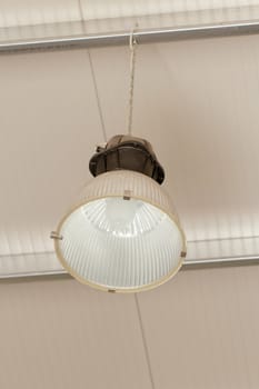 Industrial ceiling reflector with aluminium lamp vessel hanging from the roof