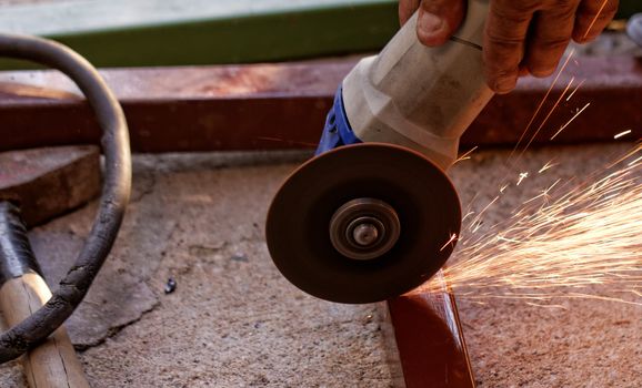 Metal sawing with hand grinder. Sparks while grinding iron.