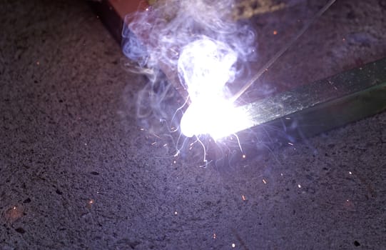 Iron welding with bright light and smoke at manufacturing