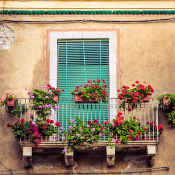 Beautiful vintage balcony with colorful flowers and wooden door
