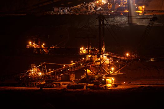 Coal mining in an open pit with huge industrial machine at night shoot