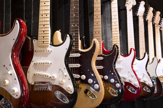 Many electric guitars hanging on wall in the music instrument shop 