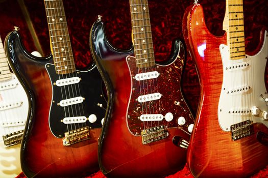 A row of electric Guitar on display with red velvet backrground,