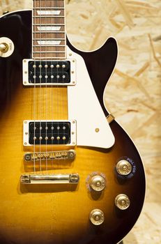 Close up of a Lacquer Golden electric guitar on wooden surface. 