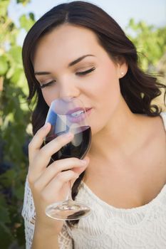 Pretty Mixed Race Young Adult Woman Enjoying A Glass of Wine in the Vineyard.