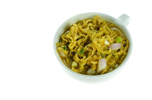 noodle dish in a yellow curry in white bowl on white background