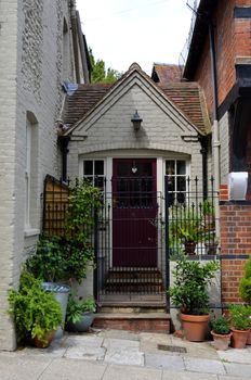Small terraced cottage showing front entrance with door and iron gate with pot plants. Shot taken in the historic town of Arundel, Sussex, England. August 2013.