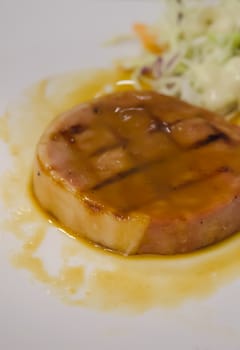 baked ham with gravy sauce on white plate served with fresh salad