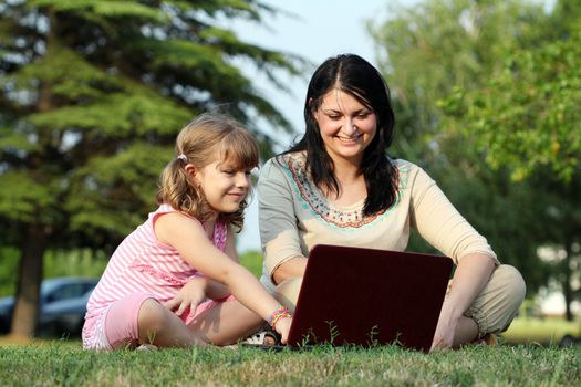 girl and child with laptop in park