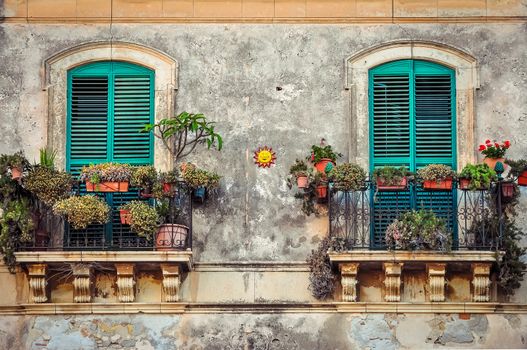 Beautiful vintage balcony with colorful flowers and wooden doors, Mediterranean style