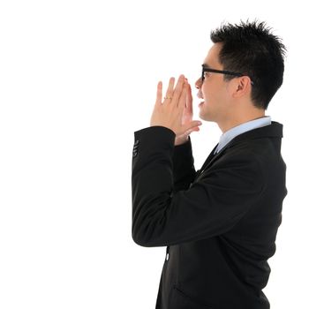 Side view young Asian business man shouting with hands cupped to his mouth, isolated on white background