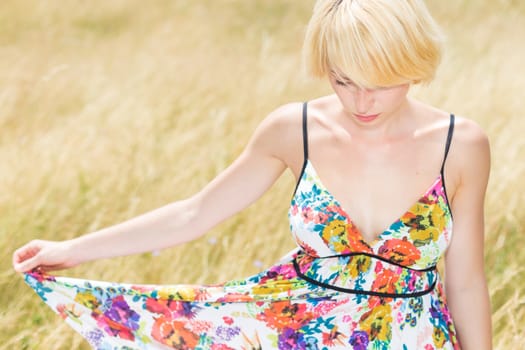 A portrait of a casual dressed beautiful young Caucasian woman outdoor in the meadow on a sunny summer day.