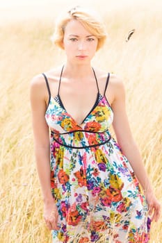 A portrait of a casual dressed beautiful young Caucasian woman outdoor in the meadow on a sunny summer day.