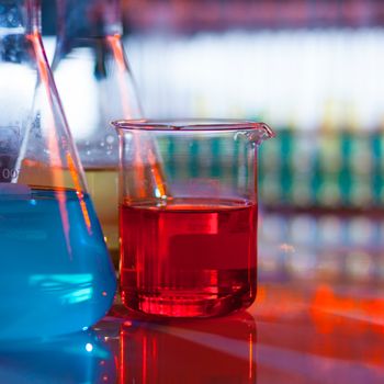 Backlit laboratory test flask containing colorful liquids.