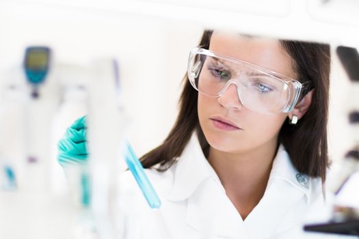 Chemical laboratory scene: attractive young PhD student scientist observing the blue indicator color shift after the solution  destillation.