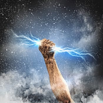 Close-up of human hand clenching lightning flash