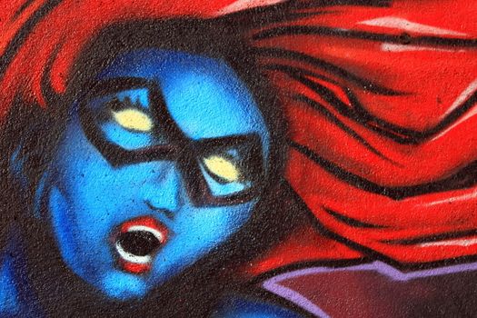 Graffiti on a wall of the blue woman head with red hair