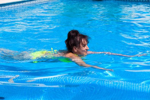 Middle-aged woman swims in the swimming pool, closeup