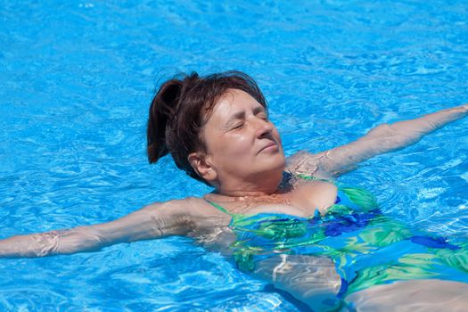 Middle-aged woman swims in the swimming pool, closeup