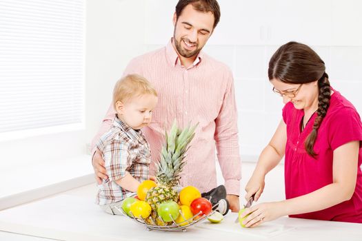 Mother is preparing fruit for child in the kitchen