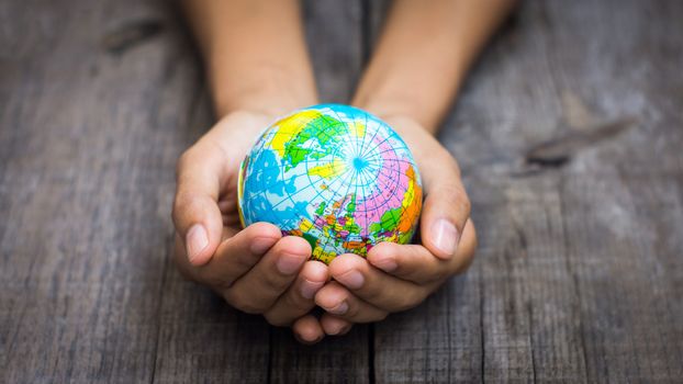 A person holding a globe on wooden background.