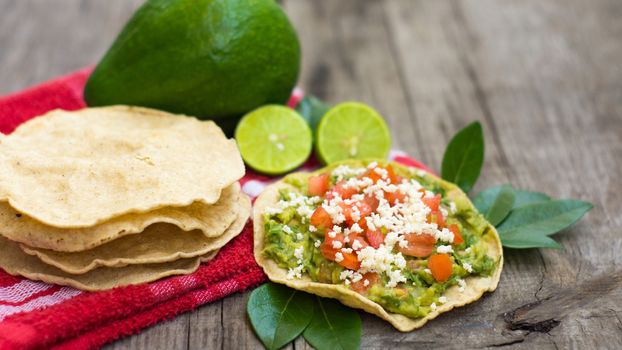 Mexican Tostadas with avocado and lemon on wooden background.