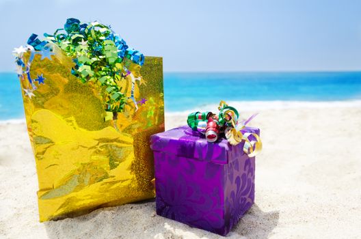 Gold Gift bag and gift box on sandy beach in sunny day- holiday concept