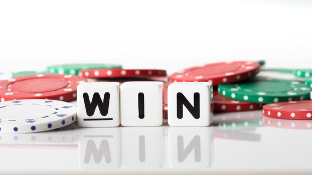 Win spelled in dice letters reflected on white isolated background with red, green and white poker chips in the background