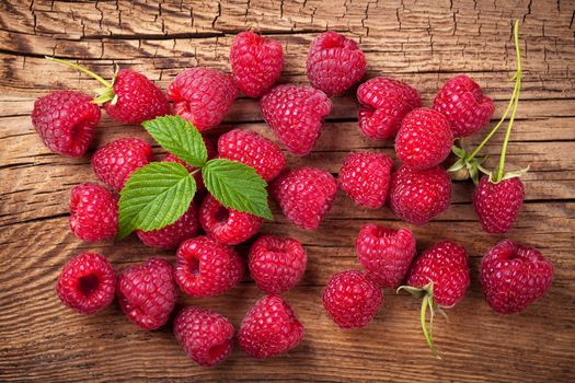 Raspberries with leaf on wooden table background. Top view