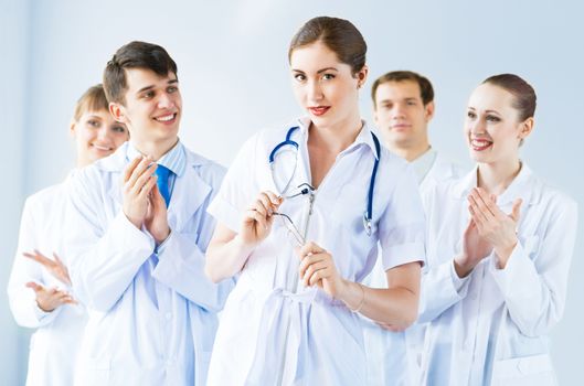 successful doctor, accepts congratulations from colleagues, stand behind him and clap