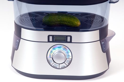 modern electric steamer with fresh cucumber on a white background
